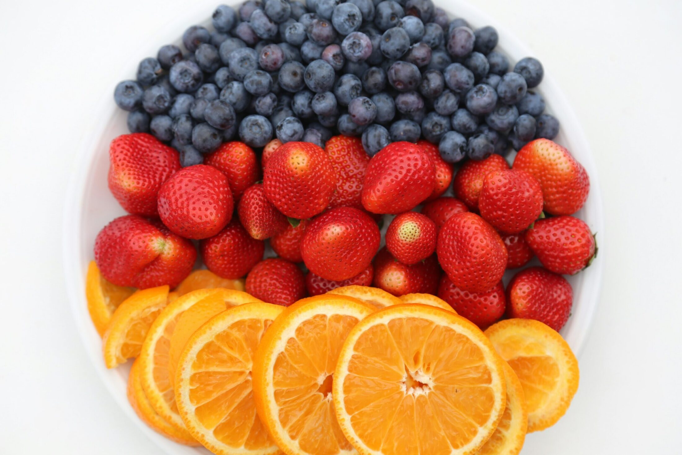 Foods rich in resveratrol including red grapes, blueberries, peanuts, and a glass of red wine on a wooden table.